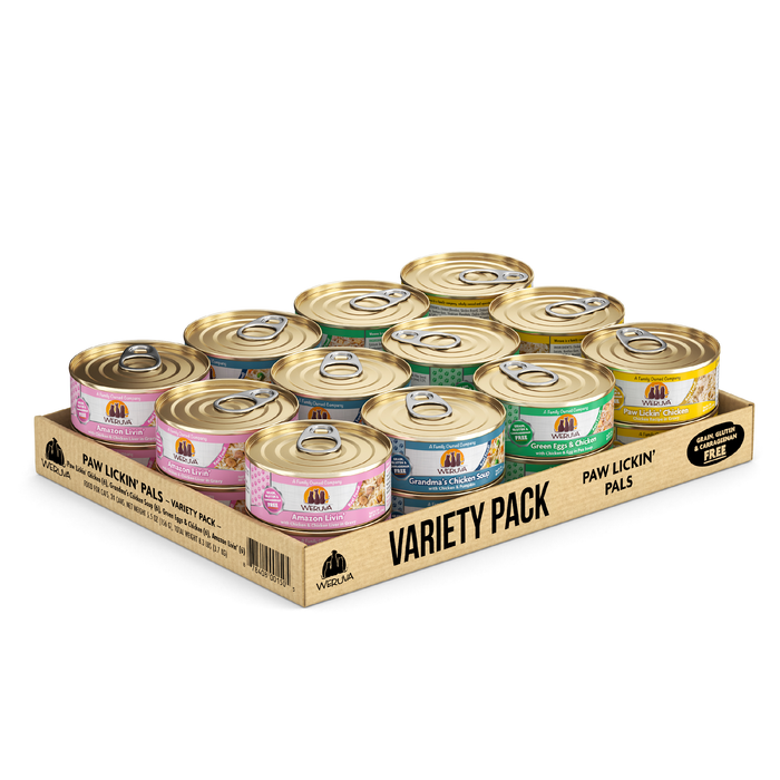 A cardboard tray holds 12 cans of Weruva Paw Lickin' Pals cat food, each with boneless white breast meat chicken and colorful pink, purple, green, and yellow labels topped with gold pull-tab lids.