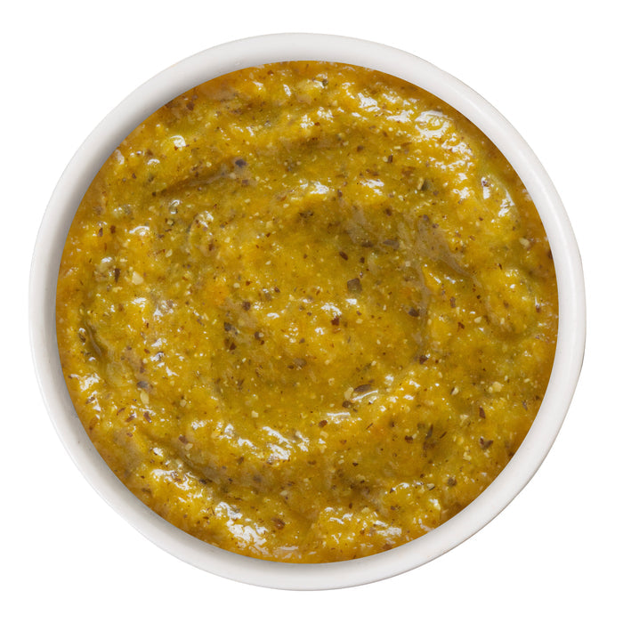 A small white bowl filled with Weruva's Pumpkin with Coconut Oil & Flaxseeds, a thick yellow-green blend with visible herbs and spices, viewed from above—formulated to support healthy digestion for pets.