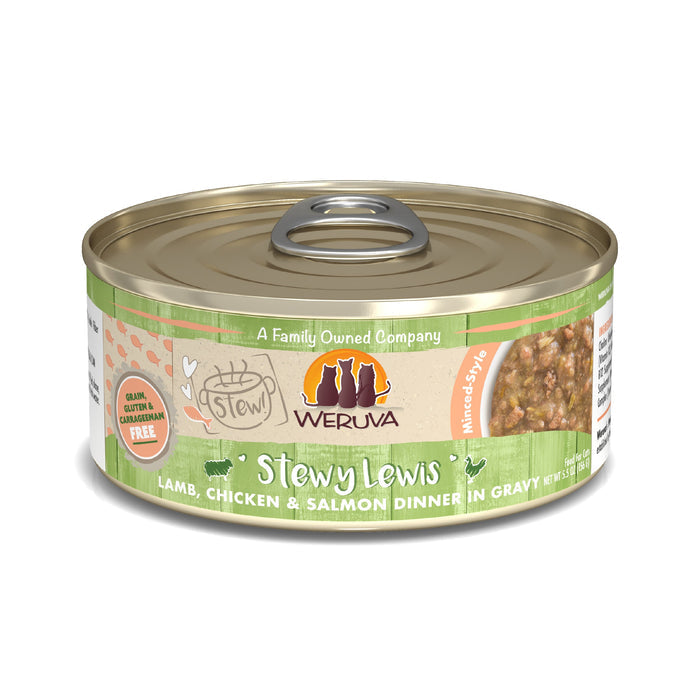 A can of Weruva Stewy Lewis cat food features a lamb, chicken & salmon dinner in gravy with grass-fed lamb and wild-caught salmon, packaged in a green-labeled can displaying ingredients and product info on the side.
